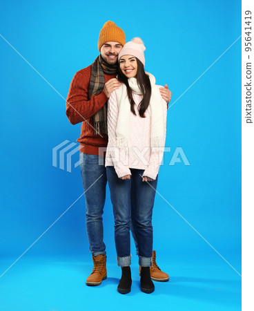 Happy young couple in warm clothes on blue background. Winter vacation 95641419