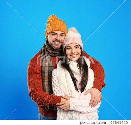 Happy young couple in warm clothes on blue background. Winter vacation 95641420