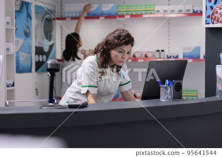 Pharmacy worker checking medication list on computer monitor, analyzing pharmaceutical treatment report for client. Pharmacist woman wearing medical uniform working in drugstore, medicine support Pharmacy worker checking medication list on computer monitor, analyzing pharmaceutical treatment report for client. Pharmacist woman wearing medical uniform working in drugstore, medicine support 95641544