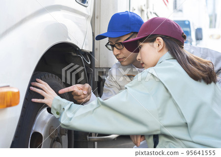 檢查卡車輪胎的男性和女性司機 檢查卡車輪胎的男性和女性司機 95641555