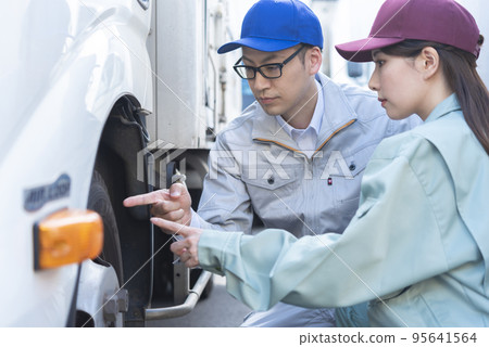 Male and female drivers inspecting truck tires 95641564