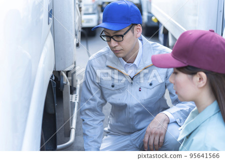 檢查卡車輪胎的男性和女性司機 95641566