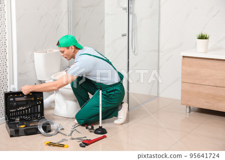 Professional plumber repairing toilet tank in bathroom 95641724