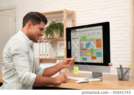 Handsome man using calendar app on computer in office 95641743