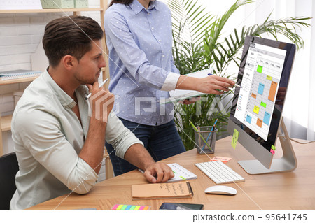 Colleagues working with calendar app on computer in office Colleagues working with calendar app on computer in office 95641745