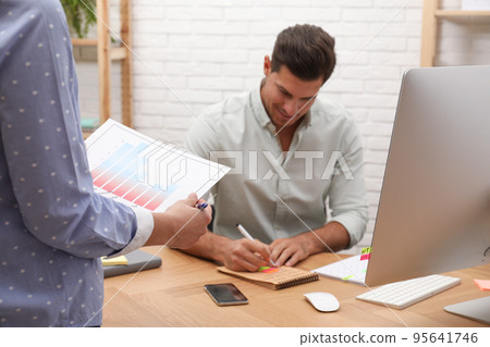Colleagues making schedule using calendar in office Colleagues making schedule using calendar in office 95641746
