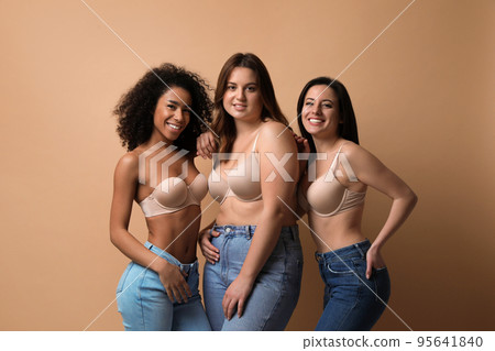 Group of women with different body types in jeans and underwear on beige background 95641840
