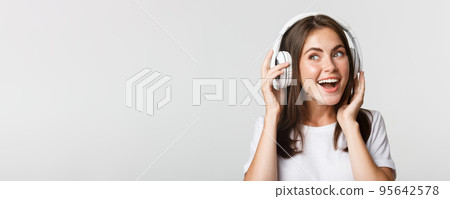 Close-up of beautiful happy girl smiling, enjoying listening music in wireless headphones 95642578