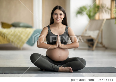Portrait of happy young pregnant woman practicing yoga at home 95643554