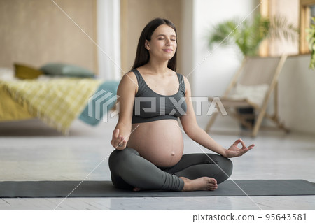 Beautiful young pregnant woman in practicing yoga in lotus position at home Beautiful young pregnant woman in practicing yoga in lotus position at home 95643581