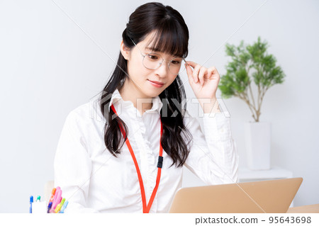 戴眼鏡的年輕女性在辦公室使用筆記本電腦 95643698