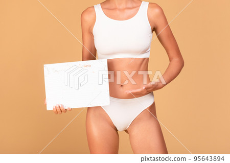 Cropped view of unrecognizable slim woman in top bra and panties holding and pointing at paper calender Cropped view of unrecognizable slim woman in top bra and panties holding and pointing at paper calender 95643894
