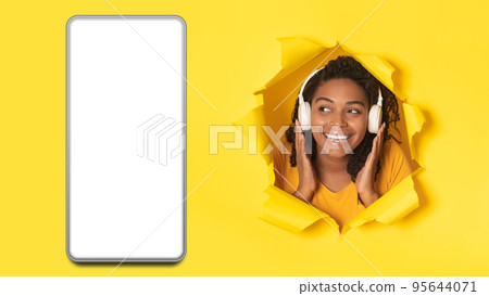 Black Woman Wearing Headphones Near Cellphone Listening Music, Yellow Background 95644071