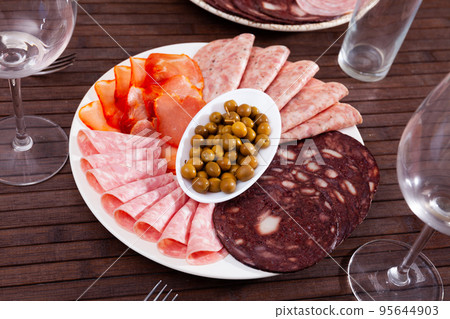Appetizing cold cuts from Spanish ham, spicy dry-cured sausages and bacon on plate 95644903