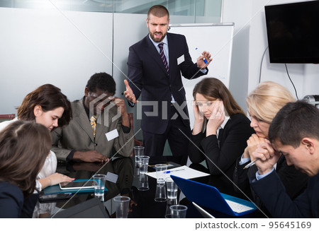 Angry boss berating his managers pointing out shortcomings Angry boss berating his managers pointing out shortcomings 95645169