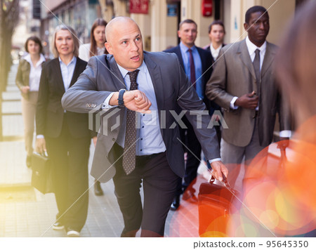 Stressed businessman checking time and running Stressed businessman checking time and running 95645350