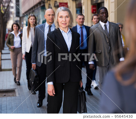 People in formal wear walking down street 95645430