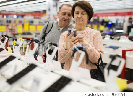 Senior couple choosing smartphone in tech store Senior couple choosing smartphone in tech store 95645463