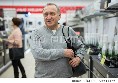 Middle aged man looking at camera while shopping in appliance store 95645476