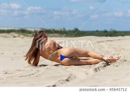 Slim woman resting on sandy beach 95645712