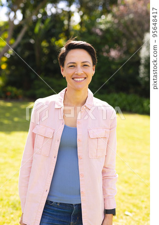 Portrait of young caucasian women wearing blue shirt and standing in the garden Portrait of young caucasian women wearing blue shirt and standing in the garden 95648417