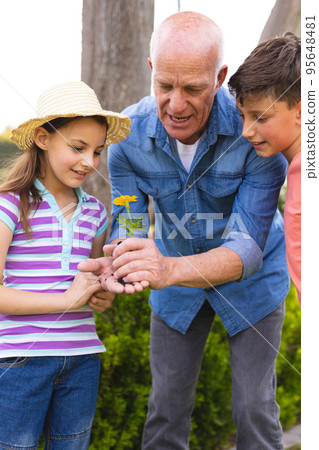 Vertical picture of caucasian children and grandfather spending time together in the garden Vertical picture of caucasian children and grandfather spending time together in the garden 95648481