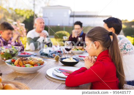 Happy caucasian family spending time together and praying before meal in the garden 95648577