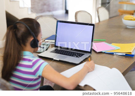 Caucasian girl learning and using laptop with copy space and headphones in living room Caucasian girl learning and using laptop with copy space and headphones in living room 95648618