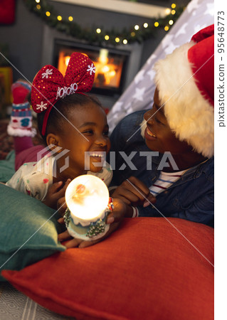 Vertical picture of african american mother and daughter lying in teepee and playing 95648773