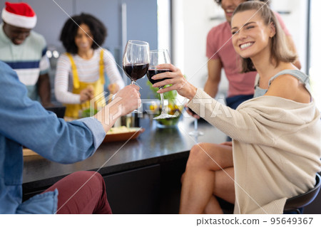 Happy diverse friends with santa hat cooking and drinking wine at christmas Happy diverse friends with santa hat cooking and drinking wine at christmas 95649367