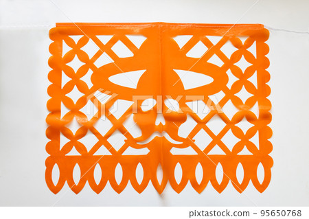 Day of the Dead, Papel Picado with a skull head wearing a hat, orange traditional Mexican paper cutting flag. Isolated on white background. 95650768