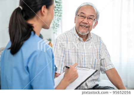 Young female doctor inquires personal data of a contented senior at home. Young female doctor inquires personal data of a contented senior at home. 95652056