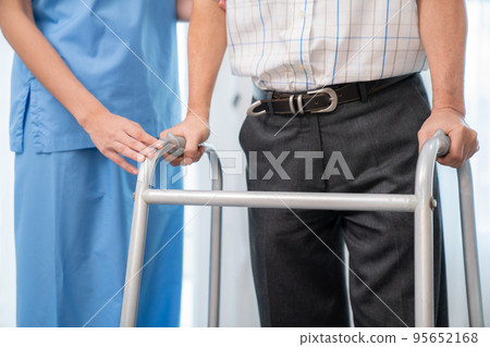 Physiotherapist assists her contented senior patient on folding walker. Physiotherapist assists her contented senior patient on folding walker. 95652168