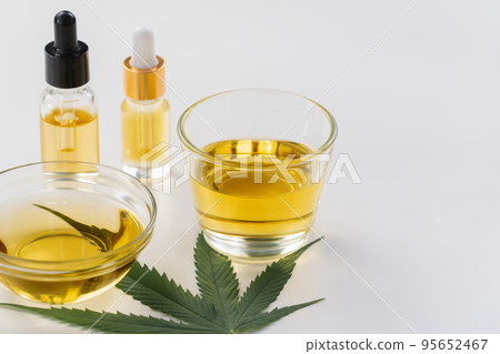 Glass bowl and bottle of legalized CBD oil, cannabis bud, and a hemp leaf 95652467