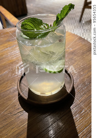 Selective facus, Delicious refreshing summer mojito with ice, lime and mint in a glass with grops. wood background. Copy space. Cold lemonade, tonic. 95654355