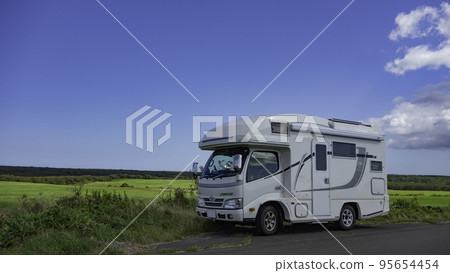 A camper with the meadows of the plains of Hokkaido in the background A camper with the meadows of the plains of Hokkaido in the background 95654454