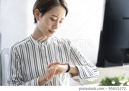 A woman who is worried about time while working, a working mother 95655272