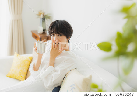 Woman in the living room yawning Woman in the living room yawning 95656248