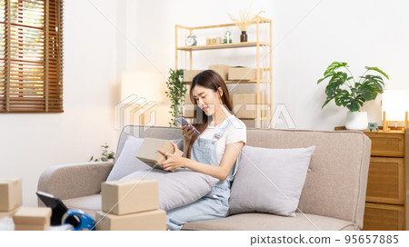 Woman taking a photo of product in box postbox with a mobile phone, Identity verification or order confirmation, Business style for working at home, Working at home and owning businesses. 95657885