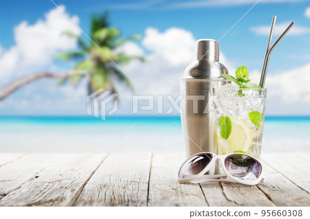 Mojito cocktail on wooden table in front of sunny sea Mojito cocktail on wooden table in front of sunny sea 95660308
