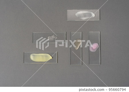 Multicolored smears of face cosmetics on laboratory glass on a gray background. Liquid face cleanser. The concept of research and creation of cosmetics 95660794