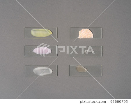 Multicolored smears of face cosmetics on laboratory glass on a gray background. Beauty and medicine concept Multicolored smears of face cosmetics on laboratory glass on a gray background. Beauty and medicine concept 95660795