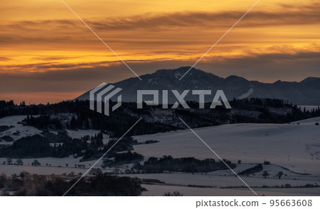 Snowy winter mountain landscape and colorful sky due sunrise over hill Poludnica in Low Tatras mountains at Slovakia 95663608
