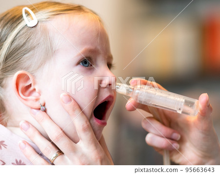 Mother cleaning baby nose with nasal aspiration 95663643