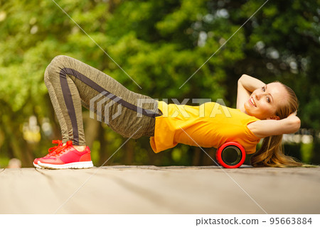 Girl doing exercises outdoor, using roller 95663884