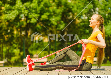 Girl doing exercise outdoor, using resistance fit band. 95663911