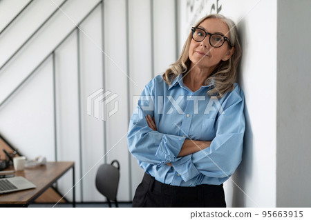 portrait of a successful Middle aged older business woman leaning against the wall in the office portrait of a successful Middle aged older business woman leaning against the wall in the office 95663915