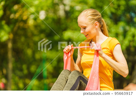 Girl doing exercise outdoor, using resistance fit band. 95663917