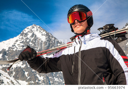 Male skier with ski goggles, helmet and skis posing in front of Lomnicky peak in High Tatras mountains Male skier with ski goggles, helmet and skis posing in front of Lomnicky peak in High Tatras mountains 95663974
