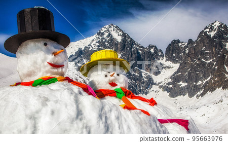 Big snowmans in winter snowy country. Peak Lomnicky stit in High Tatras mountains in Slovakia at background 95663976